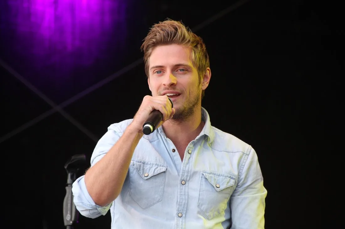 A vocalist singing into a microphone under stage lights